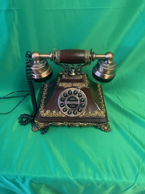 A vintage telephone is sitting on top of a green blanket.