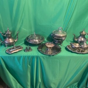 A table with silver plated tea set and other items.