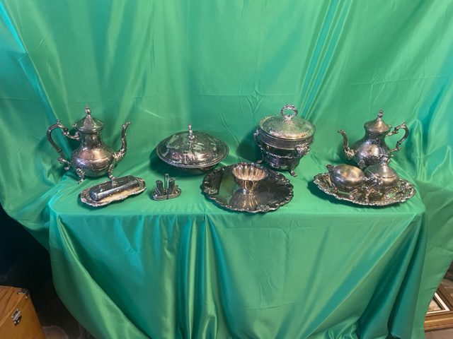 A table with silver plated tea set and other items.