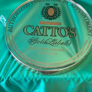 A round glass plate with the name of catto 's gold labels on it.