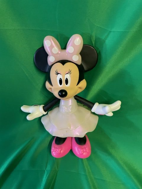 A minnie mouse doll is laying on the ground.