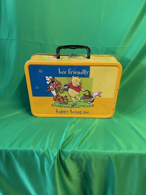 A yellow lunch box with winnie the pooh and friends on it.